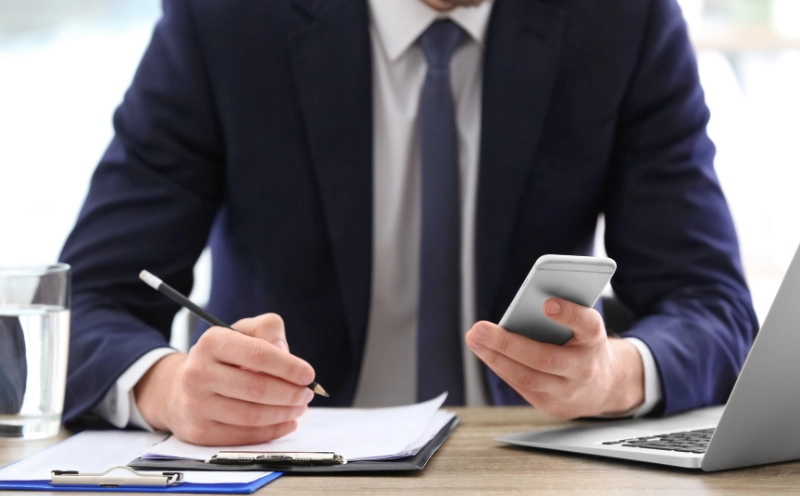 Person reviewing accident documents while speaking on phone about a Michigan car accident insurance statement